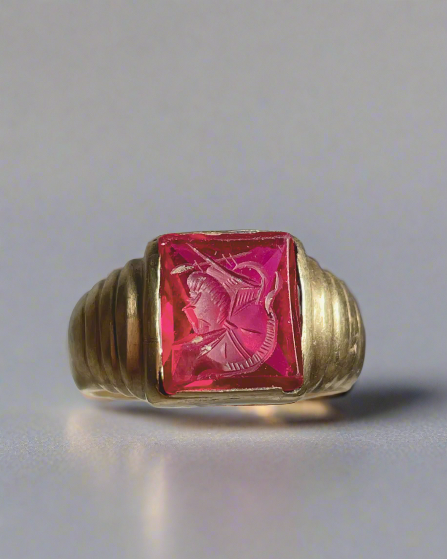 Gold ring with a pink gemstone on a gray background